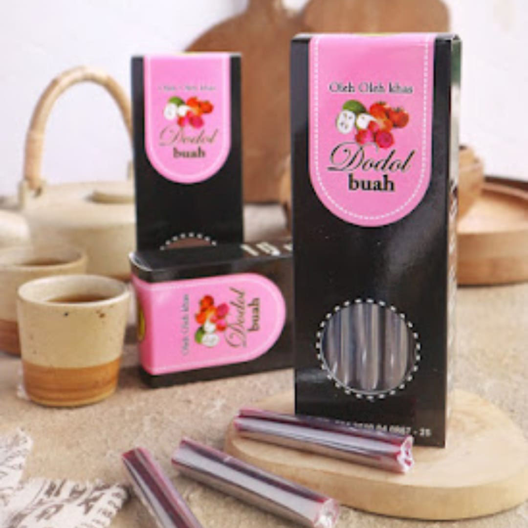 gambar oleh-oleh khas banyuwangi. Paparan Gambar : <p><strong>dodol buah manis legit dan enak berbentuk stik yang dikemas dalam kotak warna hitam dengan label warna pink.</strong></p>