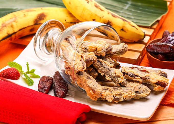 gambar sale pisang, oleh-oleh banyuwangi. Paparan Gambar : <p>Terlihat sale pisang goreng yang diletakkan dalam gelas bening dalam posisi terguling di atas meja kayu. Di sebelah sale pisang goreng terlihat 2 sale pisang murni berwarna coklat, di sebelah buah strawberi berwarna merah.</p>